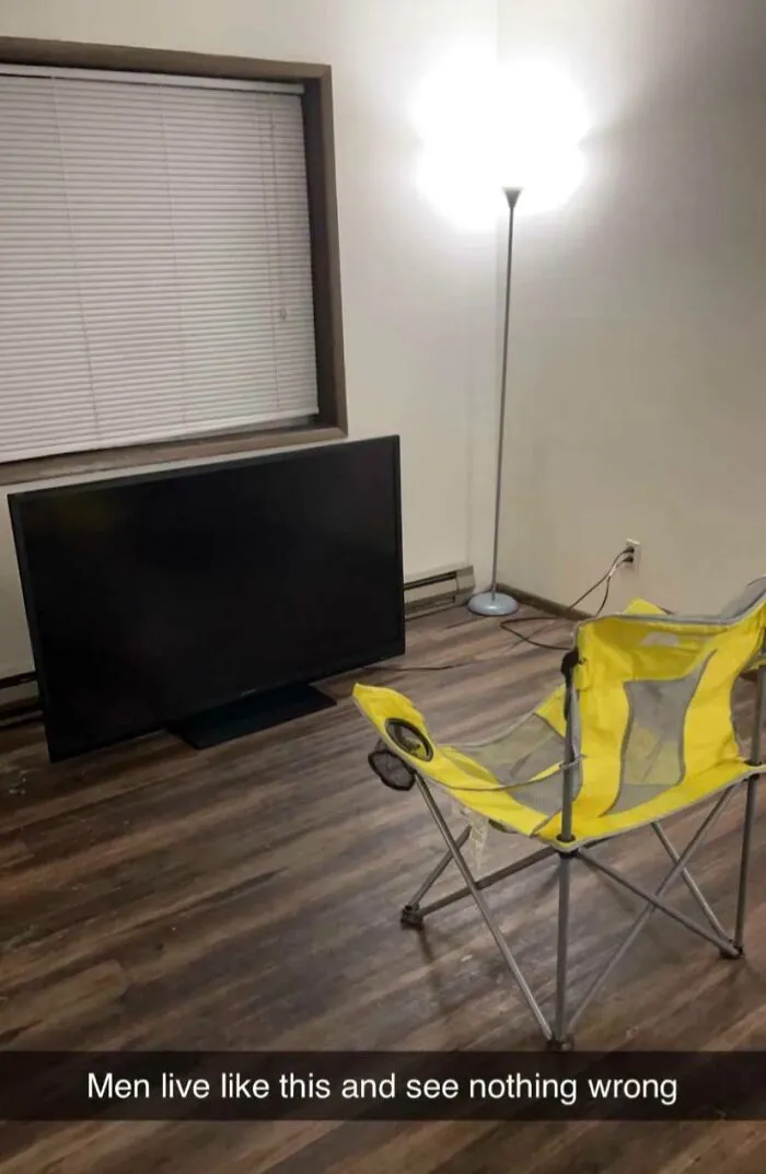 Minimalist room with a TV on the floor and a camping chair, illustrating men never growing up in a wholesome way.