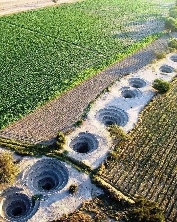 Aerial view of large deep sinkholes in farmland, illustrating mysteries of existence, reality, and the universe.