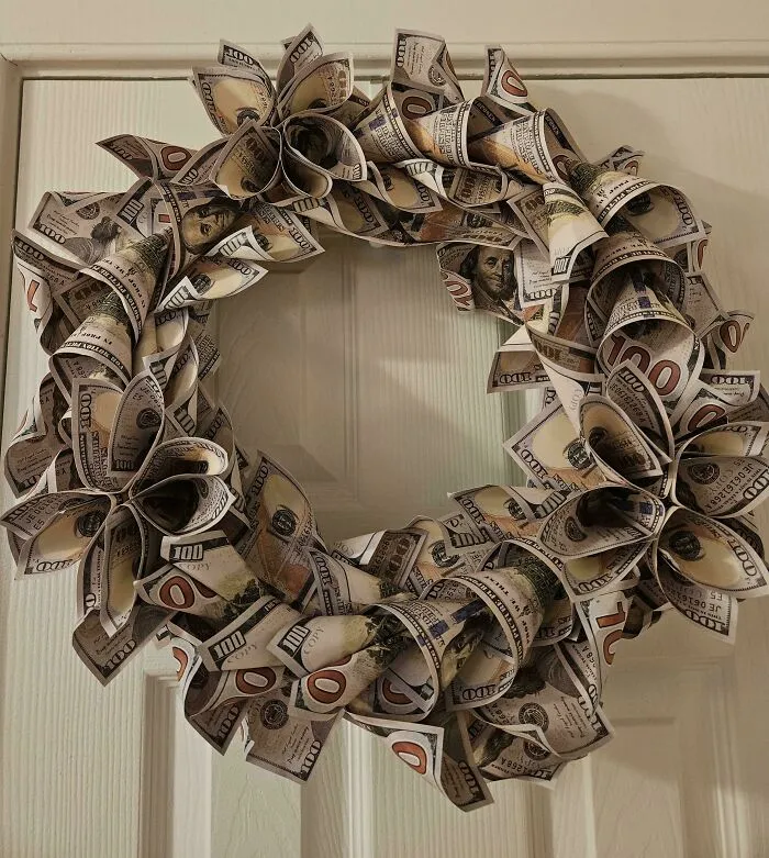 Wreath made of folded faux hundred-dollar bills hanging on a door, showcasing a playful and creative decoration.