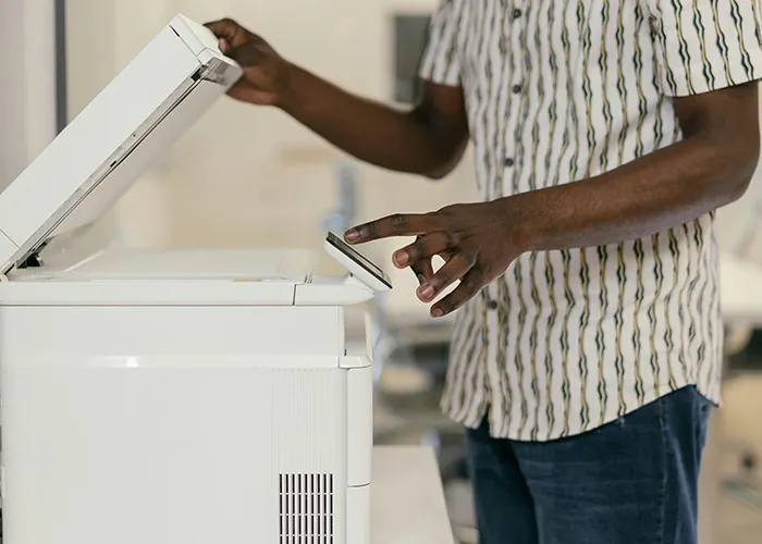 Person using a copier machine, illustrating one of the horrible gifts people have actually received in an office setting.