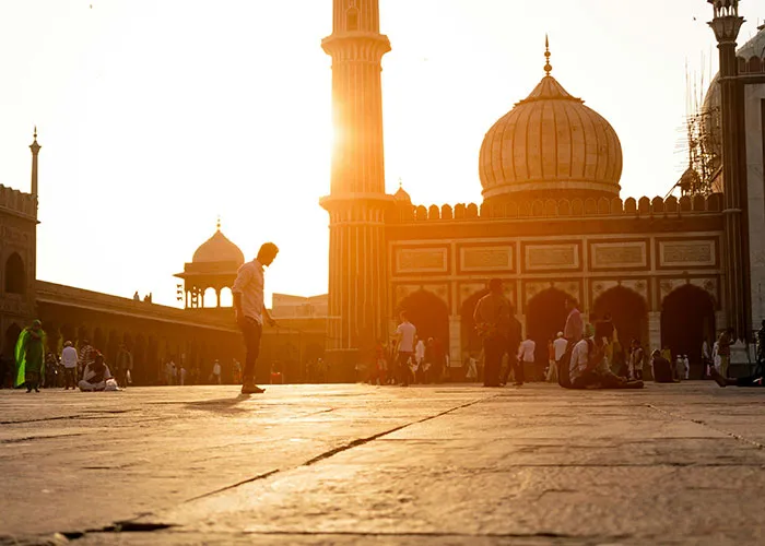People walking and sitting near historic buildings at sunset in one of the worst cities worldwide to avoid visiting.