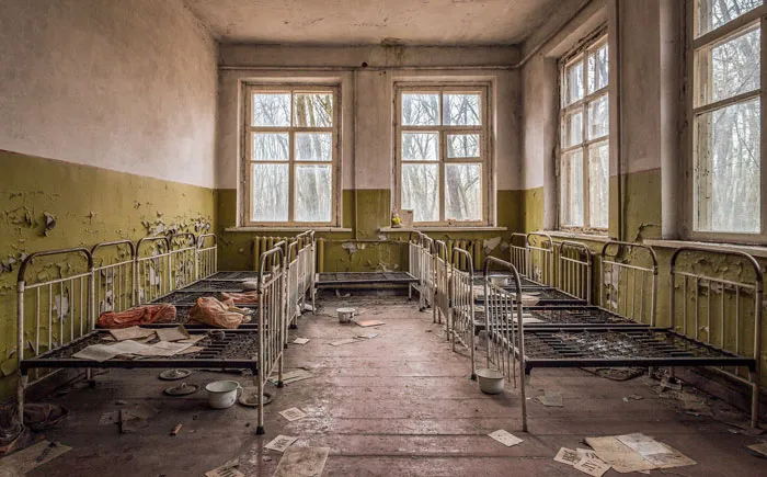 Abandoned room with rusty metal beds and peeling walls, capturing a creepy and terrifying moment for urban explorers.