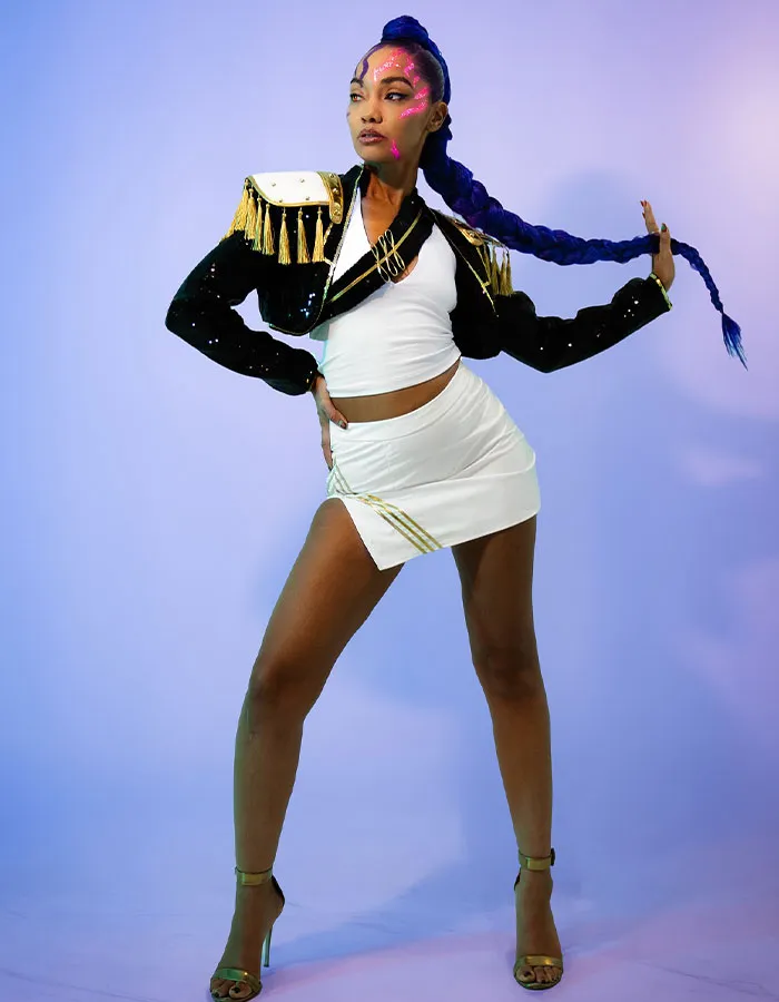 Woman in a white outfit and black jacket with neon face paint posing in a striking Halloween costume with braided hair.