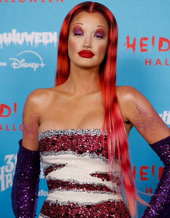 Celebrity costume with long red hair, bold makeup, and a sequined dress at Heidi Klum’s 2025 Halloween event.