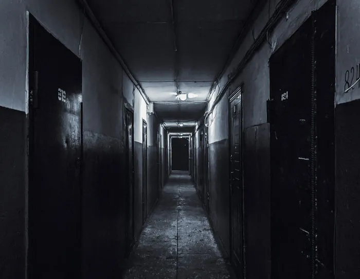 Dimly lit, narrow abandoned hallway creating creepy and terrifying moments that make urban explorers drop their flashlights and run.