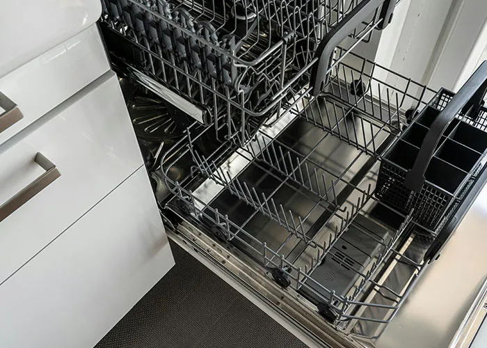 Open dishwasher with empty racks inside a modern kitchen, illustrating genius cleaning hacks inspired by laziness.