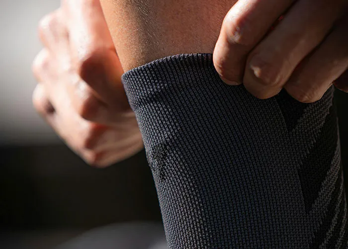 Close-up of hands pulling up a black sock, illustrating simple and genius cleaning hacks inspired by laziness.
