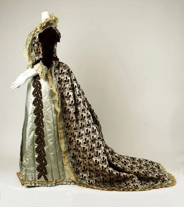 Victorian Edwardian dress with intricate patterns and velvet accents displayed on a mannequin in a studio setting