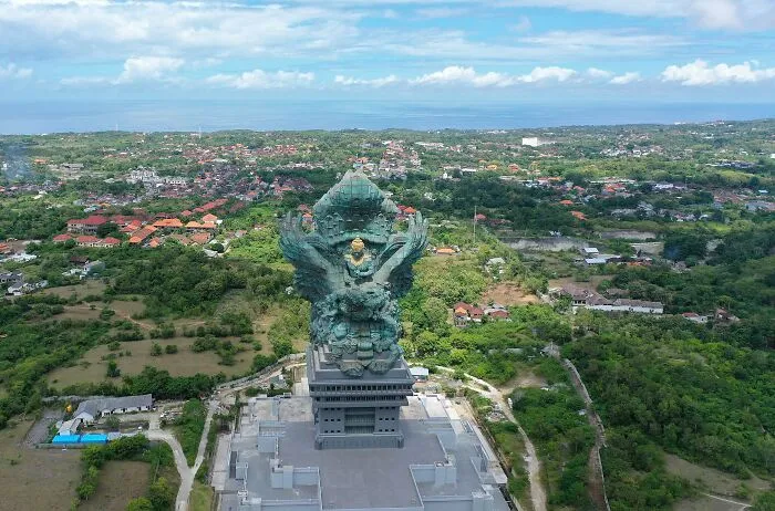 Giant intricate sculpture towering over green landscape, highlighting spectacular sculptures across the globe for travel bucket lists.