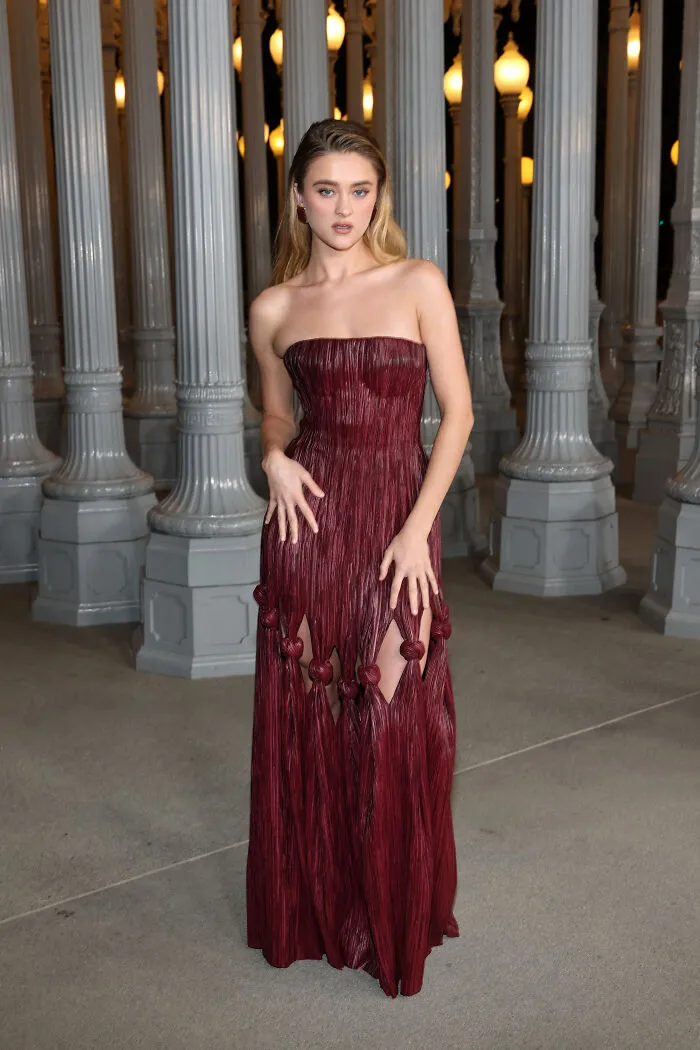 Woman wearing a strapless maroon gown with knot details at 2025 LACMA Art and Film Gala showcasing best and worst outfits.