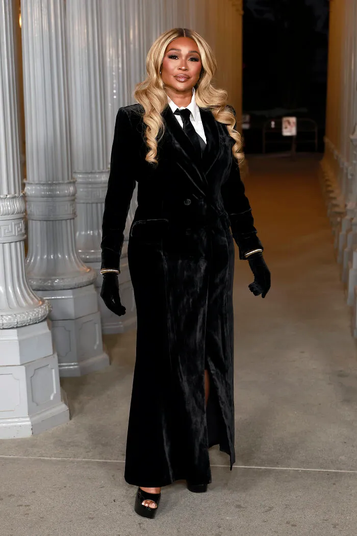 Woman in a black velvet coat dress and gloves posing at 2025 LACMA Art and Film Gala showcasing best and worst outfits.