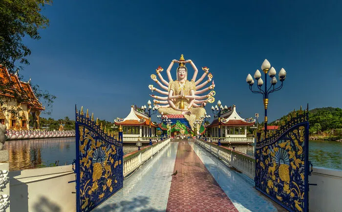 Massive multi-armed sculpture at a temple entrance, one of the spectacular sculptures across the globe for travelers.