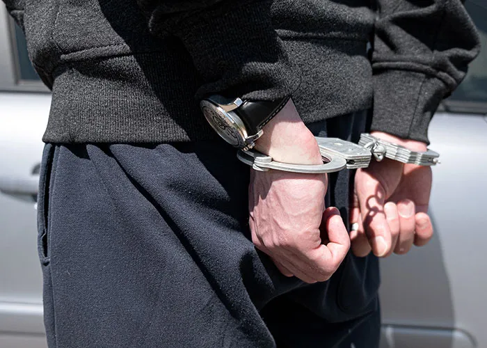 Person in handcuffs wearing a black sweatshirt and watch, illustrating wild family dramas and chaotic situations.