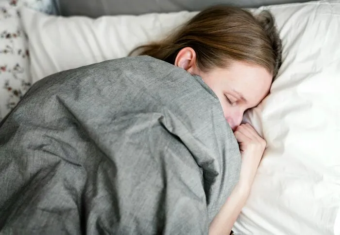Person sleeping in bed under a gray blanket, illustrating mysterious medical issues and the diagnoses that clarified them.