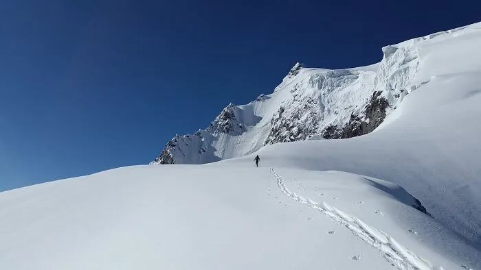 A lone hiker traversing a vast snowy mountain landscape, evoking bizarre and creepy park ranger experiences.
