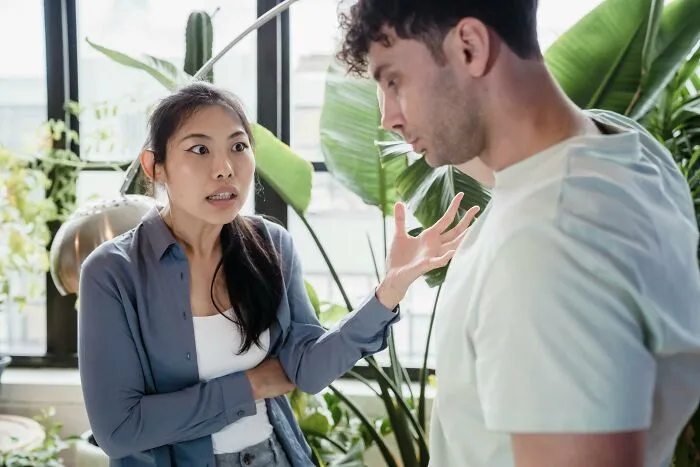 Woman expressing frustration to man during a tense conversation about toxic relationship traits in a bright indoor setting.