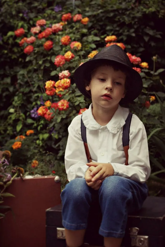 Child sitting thoughtfully in garden with colorful flowers, capturing funny and serious moments parents faced raising monsters.