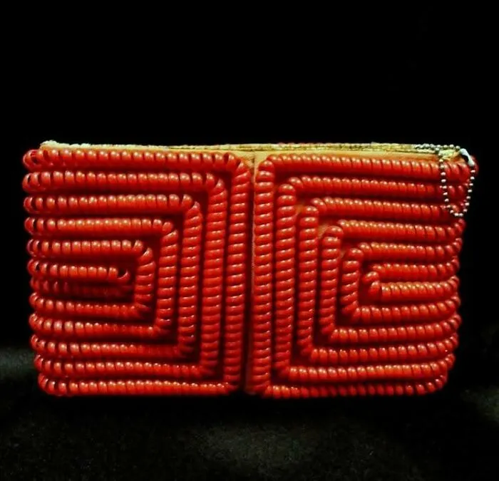 Ancient red beaded artifact with intricate spiral patterns, a very old object surviving from our ancestors' time.