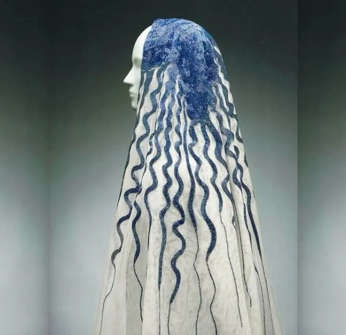 Ancient textile with blue wavy patterns displayed on a white mannequin showcasing very old objects from our ancestors.