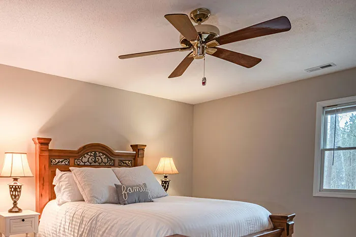 Cozy bedroom with wooden bed and ceiling fan illustrating scariest things people have woken up to stories.