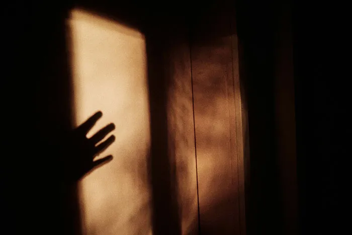 Shadow of a hand on a dim wall, evoking the scariest things people have woken up to in frightening moments.