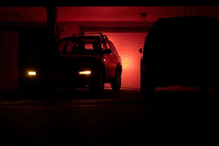 Two cars parked in a dark driveway at night with one car’s headlights on, evoking the scariest things people have woken up to.