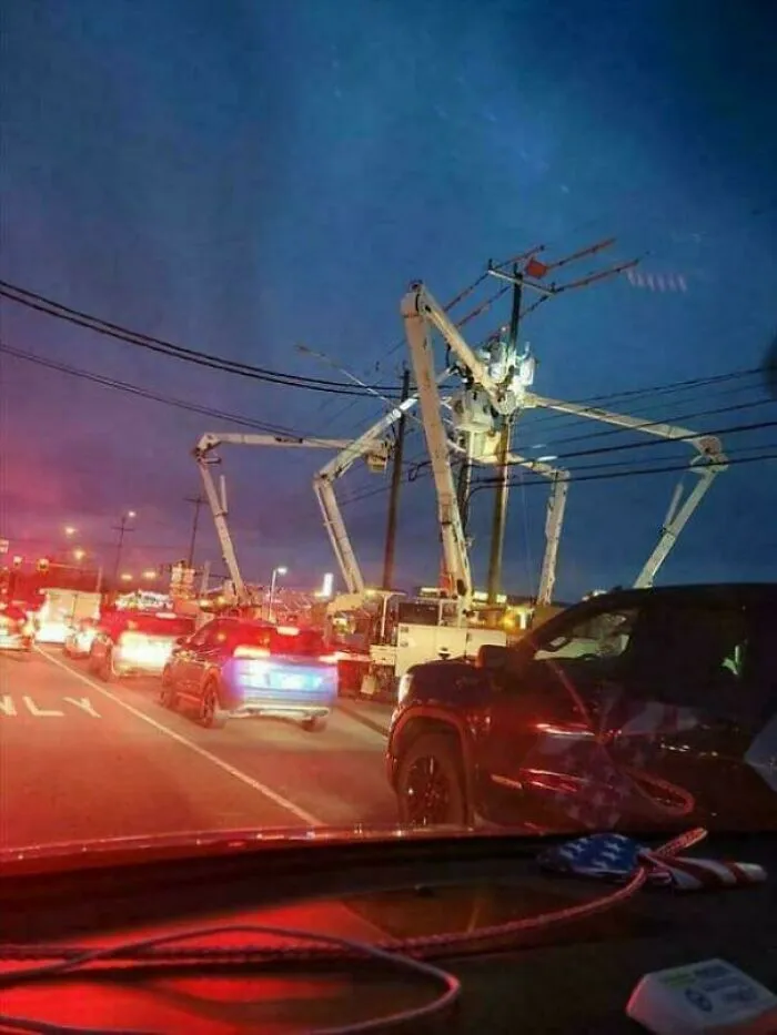 Night scene of large mechanical arms resembling a spider near power lines, evoking megalophobia fear in urban traffic.