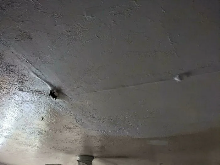 Damaged ceiling with holes and water stains in a rental property showing common rental nightmares landlords tried to cut corners on.