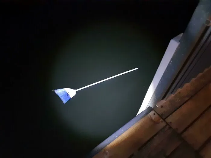 Broom appearing to float above dark water in a confusing photo that tricks the brain for a moment.