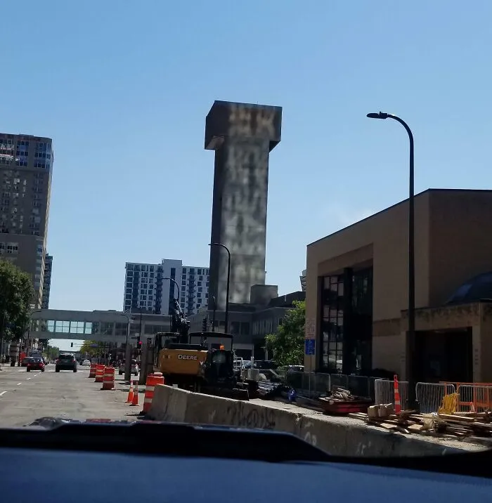 Construction site on a city street with a tall, oddly shaped tower creating a confusing visual for the brain to catch up.