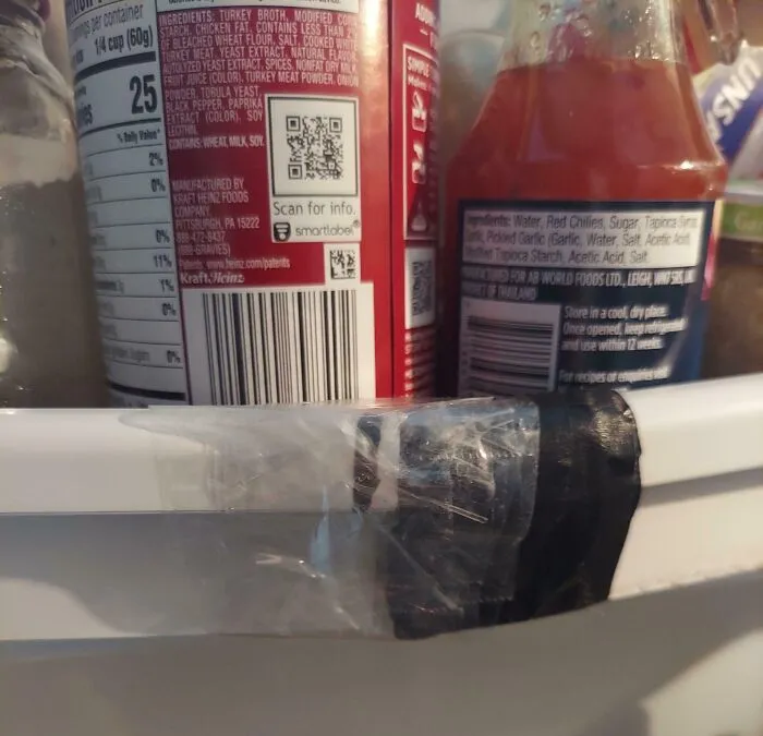 Refrigerator door with cracked hinge taped together, showcasing a rental nightmare where landlords cut corners and got exposed.
