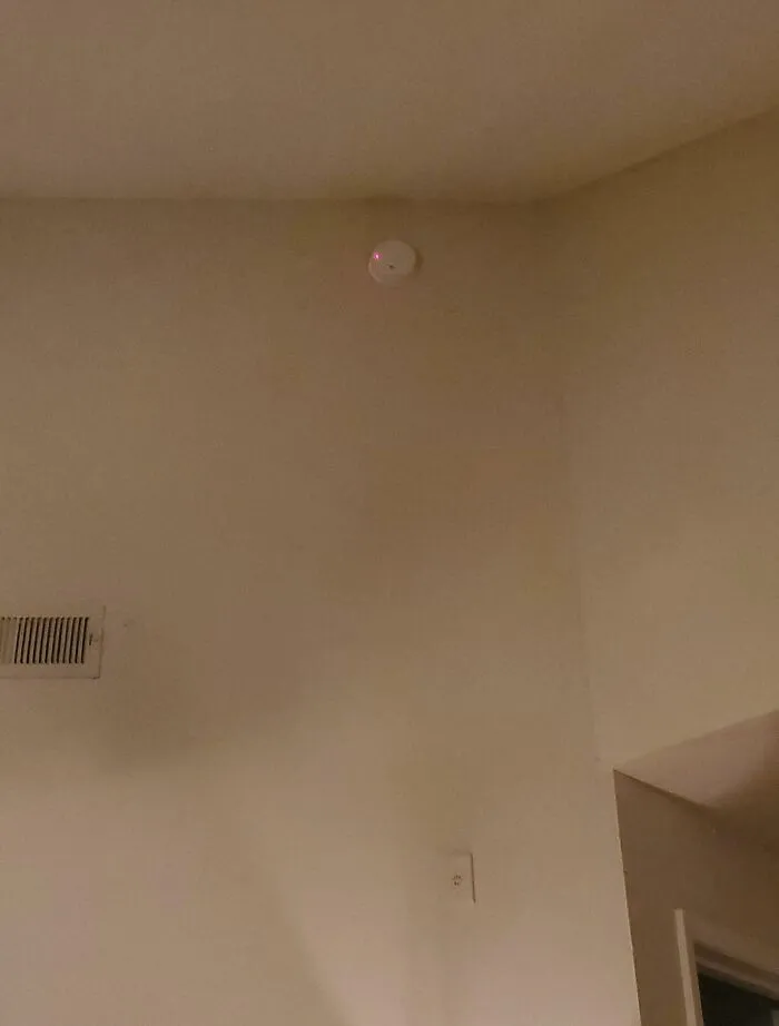 Smoke detector installed too high in corner of rental unit ceiling, illustrating rental nightmares and landlord corner-cutting exposed.