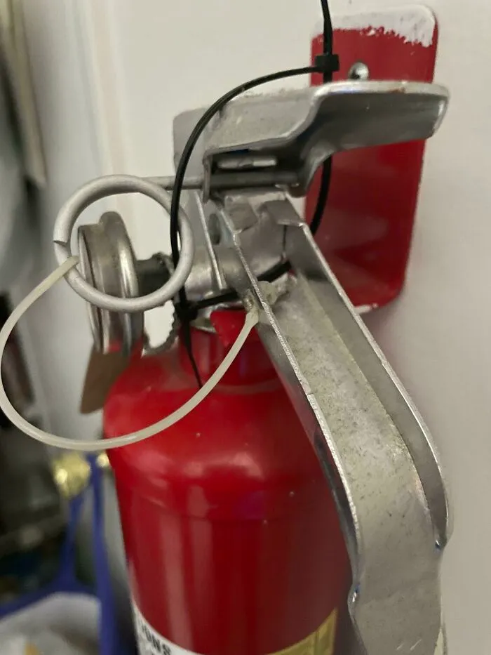 Close-up of a fire extinguisher with a damaged safety pin, illustrating rental nightmares where landlords cut corners and got exposed.
