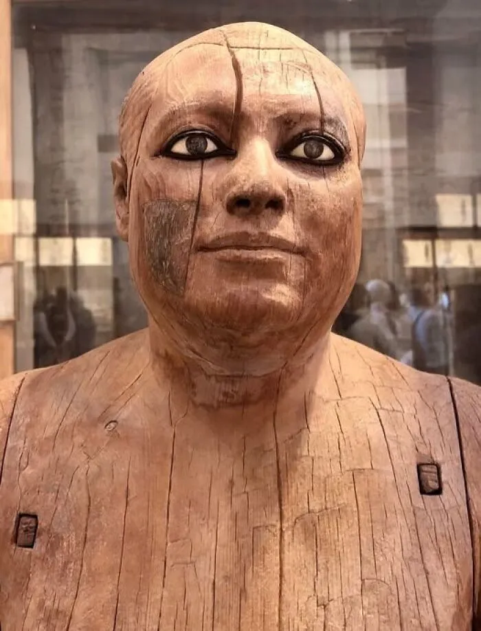 Ancient Egyptian wooden statue with detailed facial features and large eyes, showcasing incredible artifact craftsmanship.