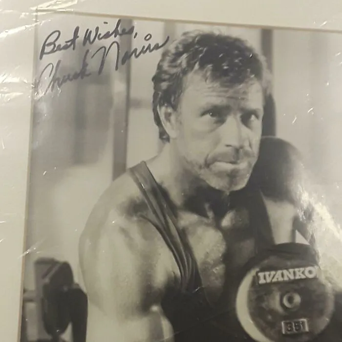 Autographed vintage black and white photo of a muscular man holding a dumbbell, one of the bizarre Christmas gifts.