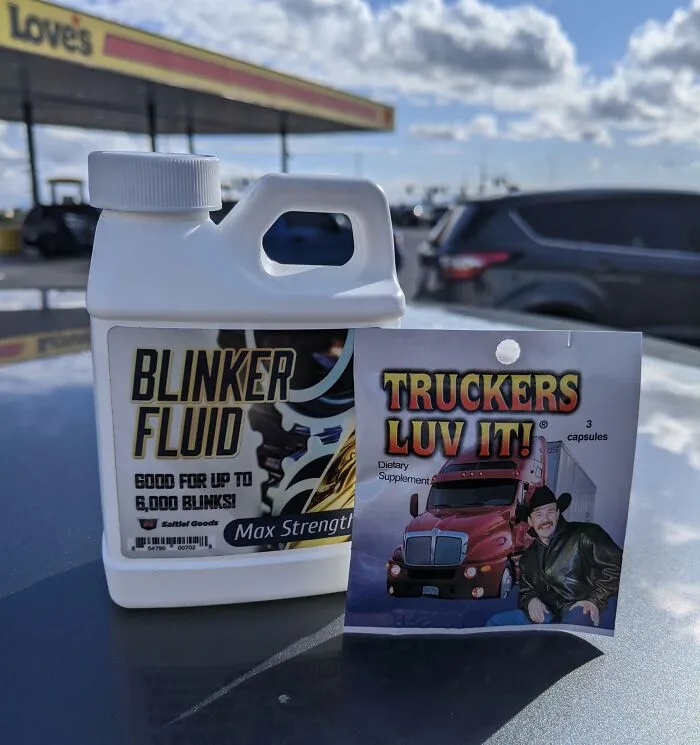 Bottle of blinker fluid and a packet of trucker-themed supplements shown as bizarre Christmas gifts outdoors.
