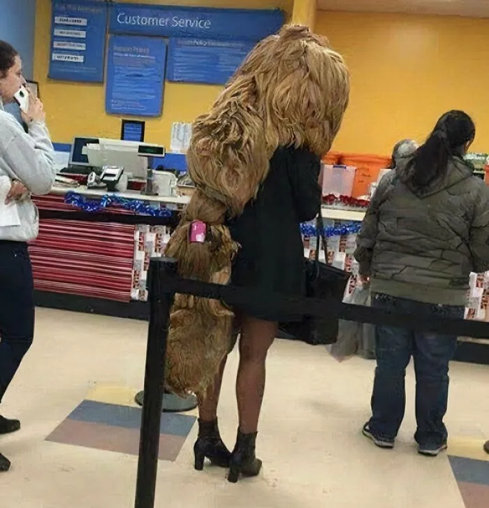Person wearing an unusual large furry costume standing in line at Walmart customer service area.