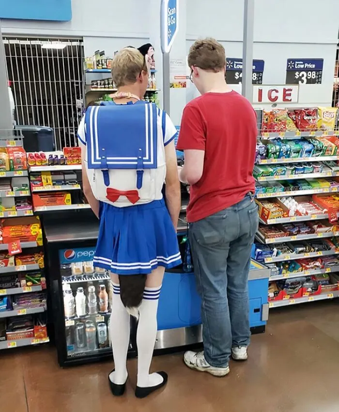 Person dressed in a blue sailor outfit with a tail shopping at a Walmart checkout with another customer nearby.