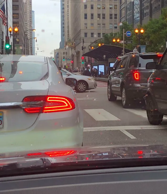 Tráfico urbano congestionado con varios autos en la calle, reflejando momentos de personas portándose mal en la vía pública.