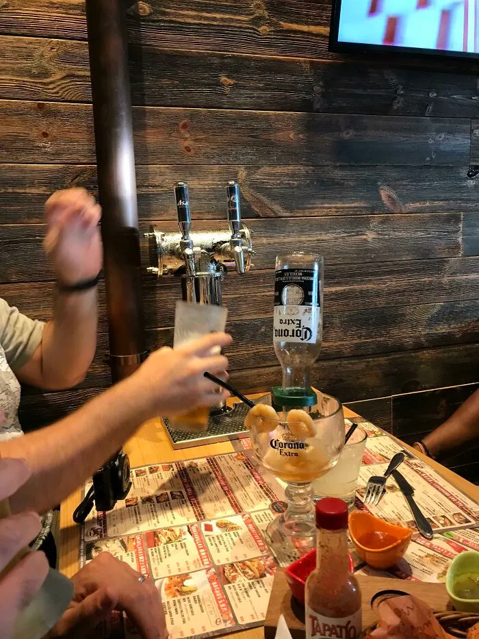 Person serving beer from a tap with a Corona Extra bottle in a shrimp cocktail, showcasing impressive country beverage ideas.