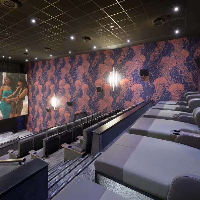 Modern movie theater with reclining loungers and jellyfish patterned walls, showcasing impressive country innovations.