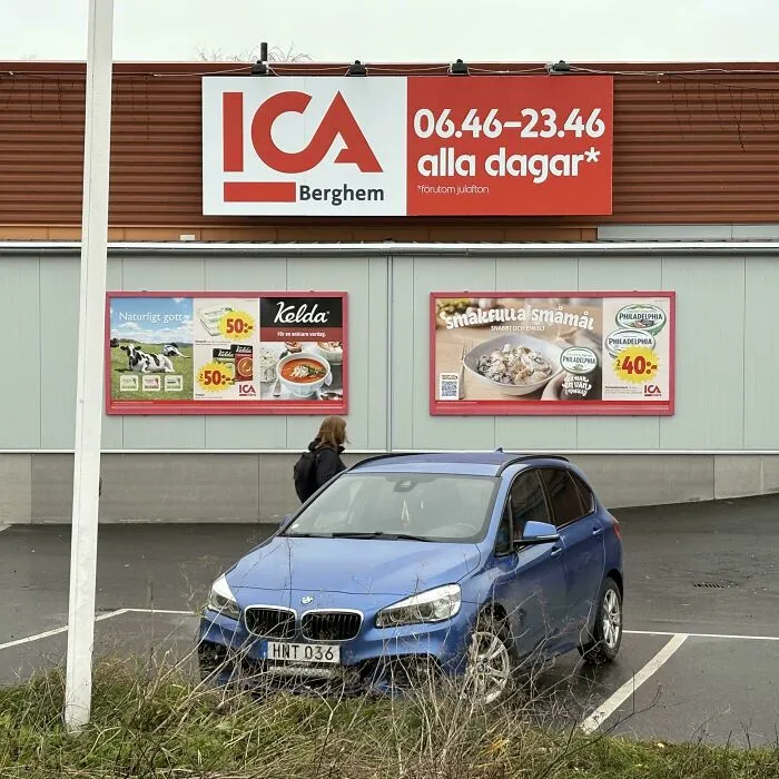 Blue BMW parked outside a Swedish ICA store showcasing impressive things countries implemented in everyday retail settings.