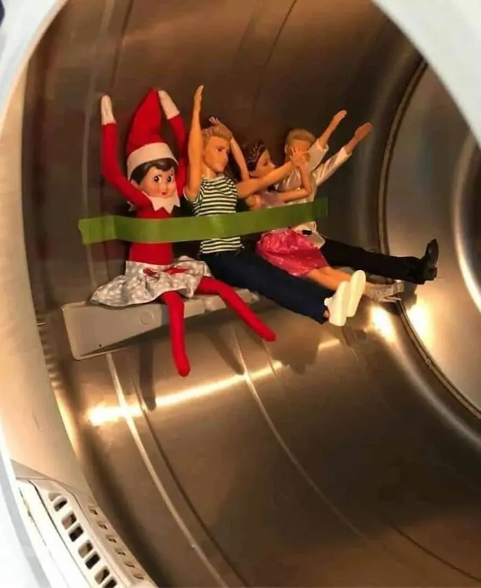 Elf on the Shelf and dolls tied with tape inside a washing machine, creating a playful and mischievous scene.