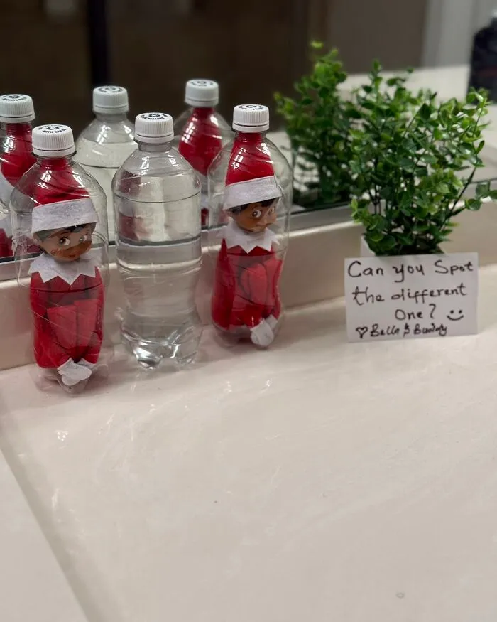 Elf on the Shelf hiding inside water bottles in a bathroom with a note challenging to spot the different one.