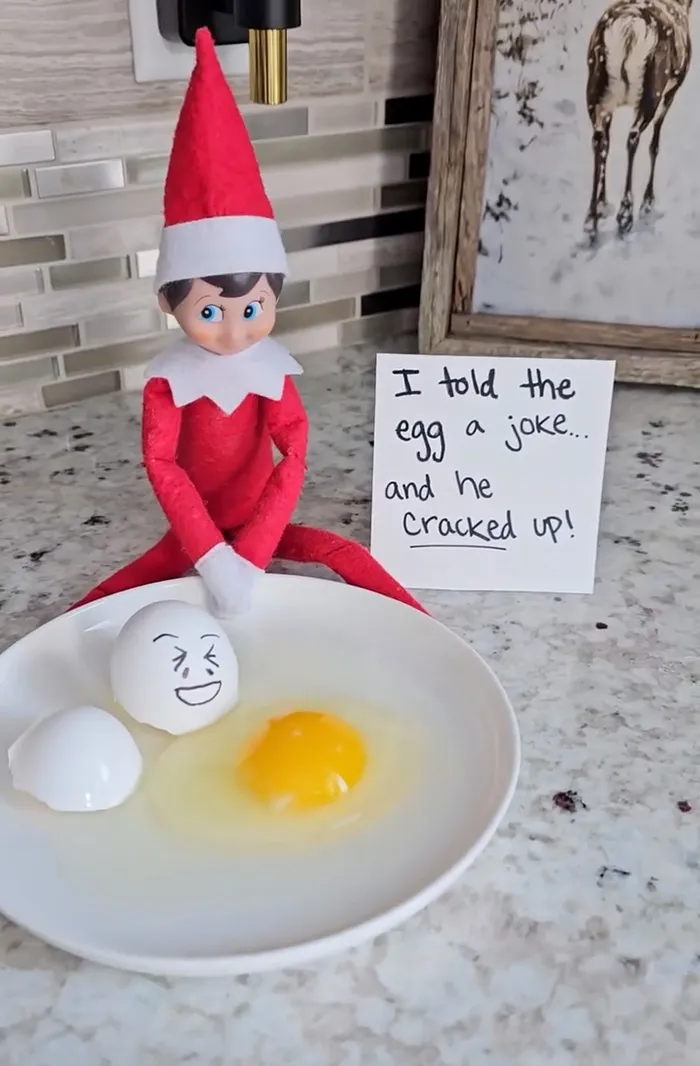 Elf on the Shelf prank with cracked egg and funny note about telling the egg a joke on kitchen counter surface
