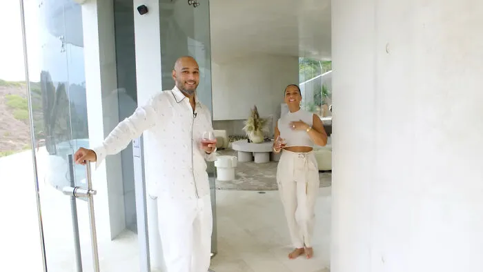 Two people smiling and holding drinks while standing in a modern home, highlighting people think celebrities closet skeletons.