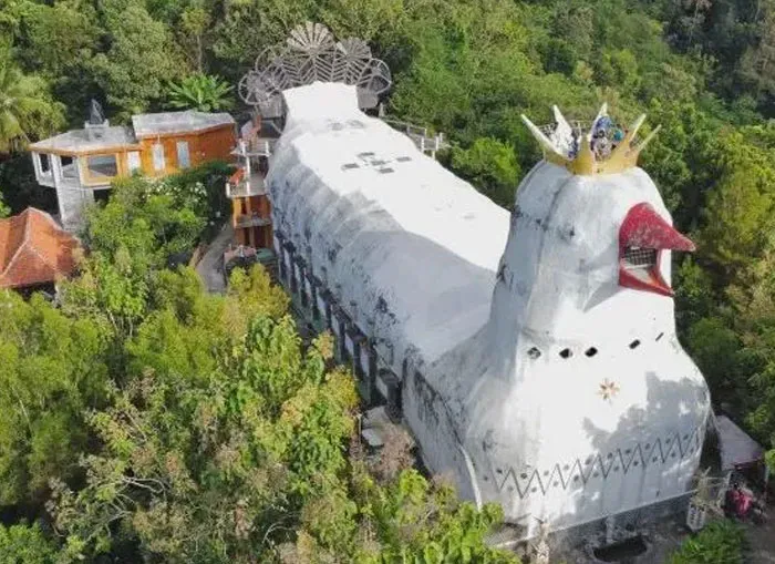Bread-shaped bread factory building with a crown, nestled in lush greenery, showcasing unique architectural design.