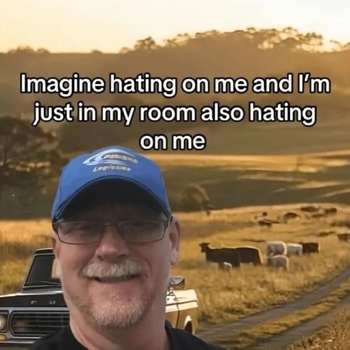 Man wearing a blue cap and glasses smiling in a field with cows, funny unhinged meme about self-hate.