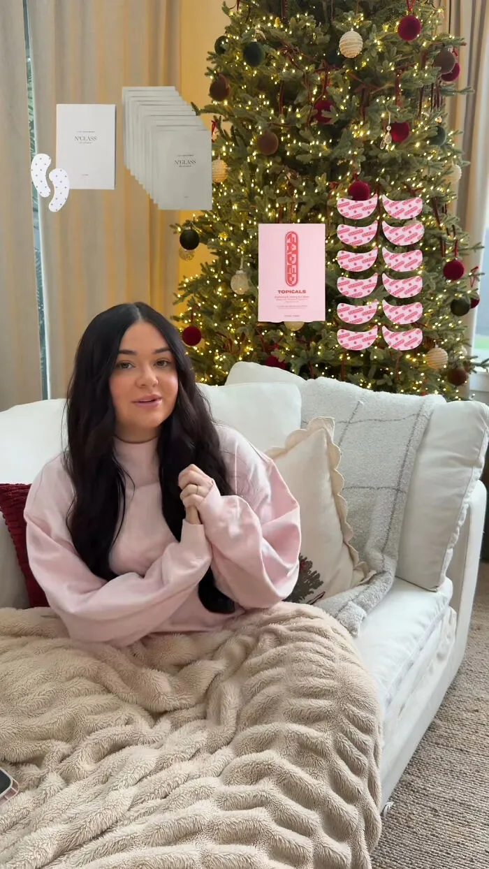 Woman sitting on couch by Christmas tree, sharing popular Christmas gifts that people highly recommend.