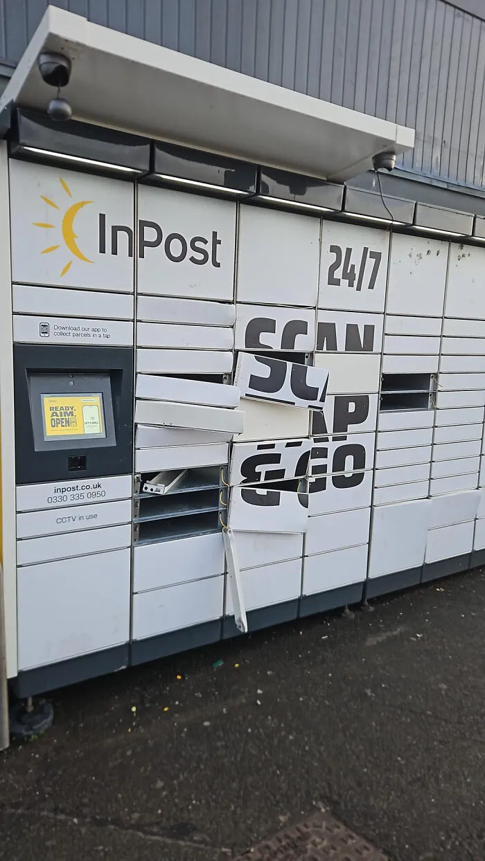 Damaged InPost delivery locker with broken doors and torn Scan & Go sign outdoors.